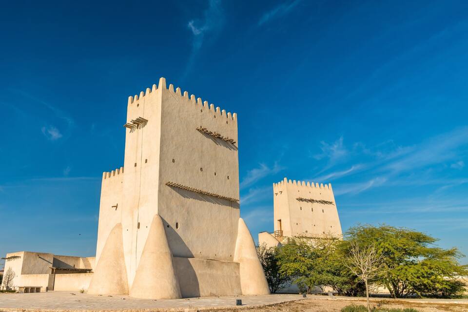 A large, beige castle with two prominent towers and a surrounding courtyard.