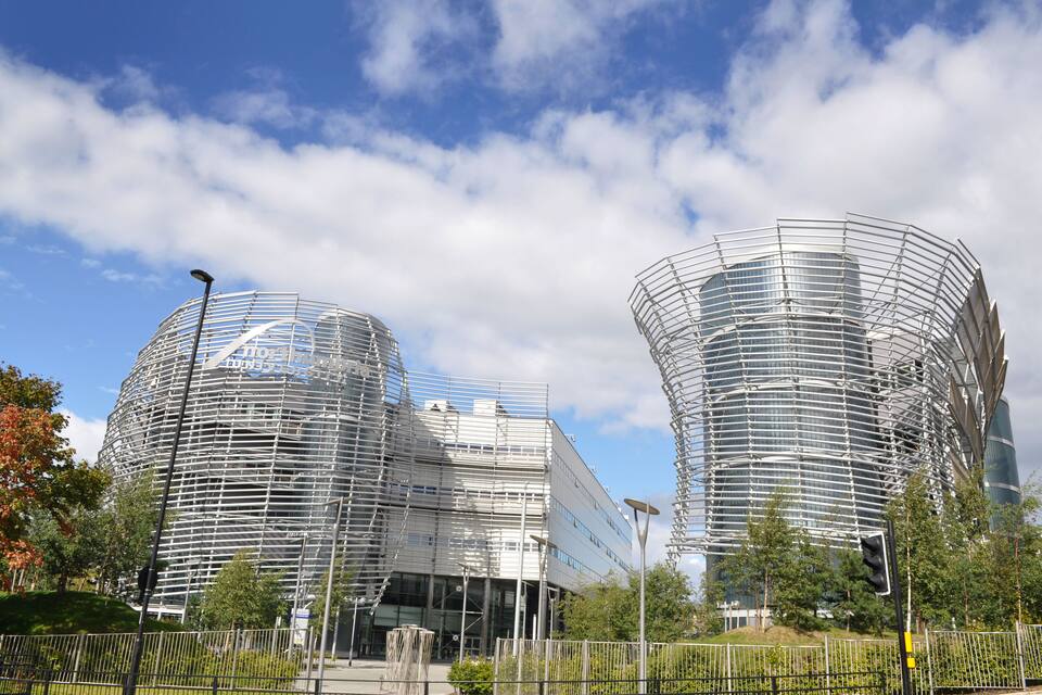 Een modern gebouw met een rond ontwerp, omringd door bomen en een heldere lucht.