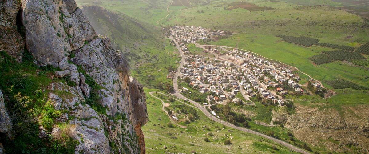 A town nestled in a valley with a prominent rocky cliff on the left.