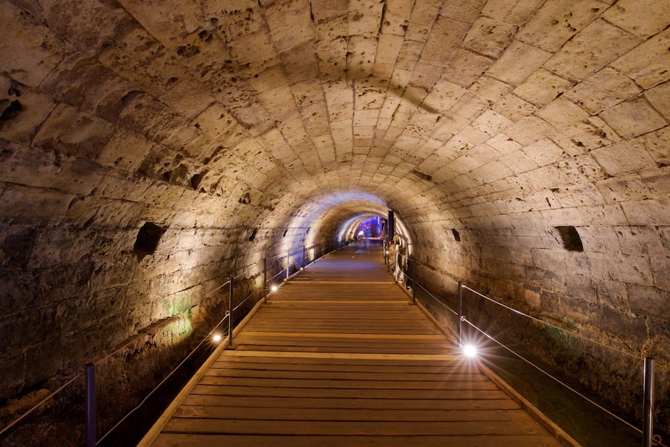 A stone tunnel with wooden walkways and metal railings.