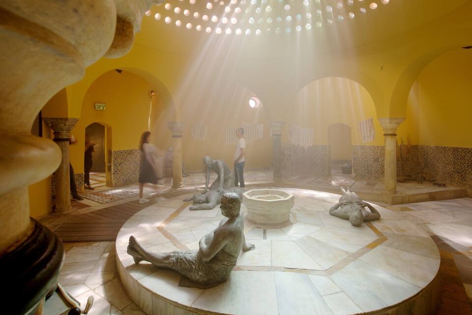 A historic interior with arches, a central fountain, and statues.