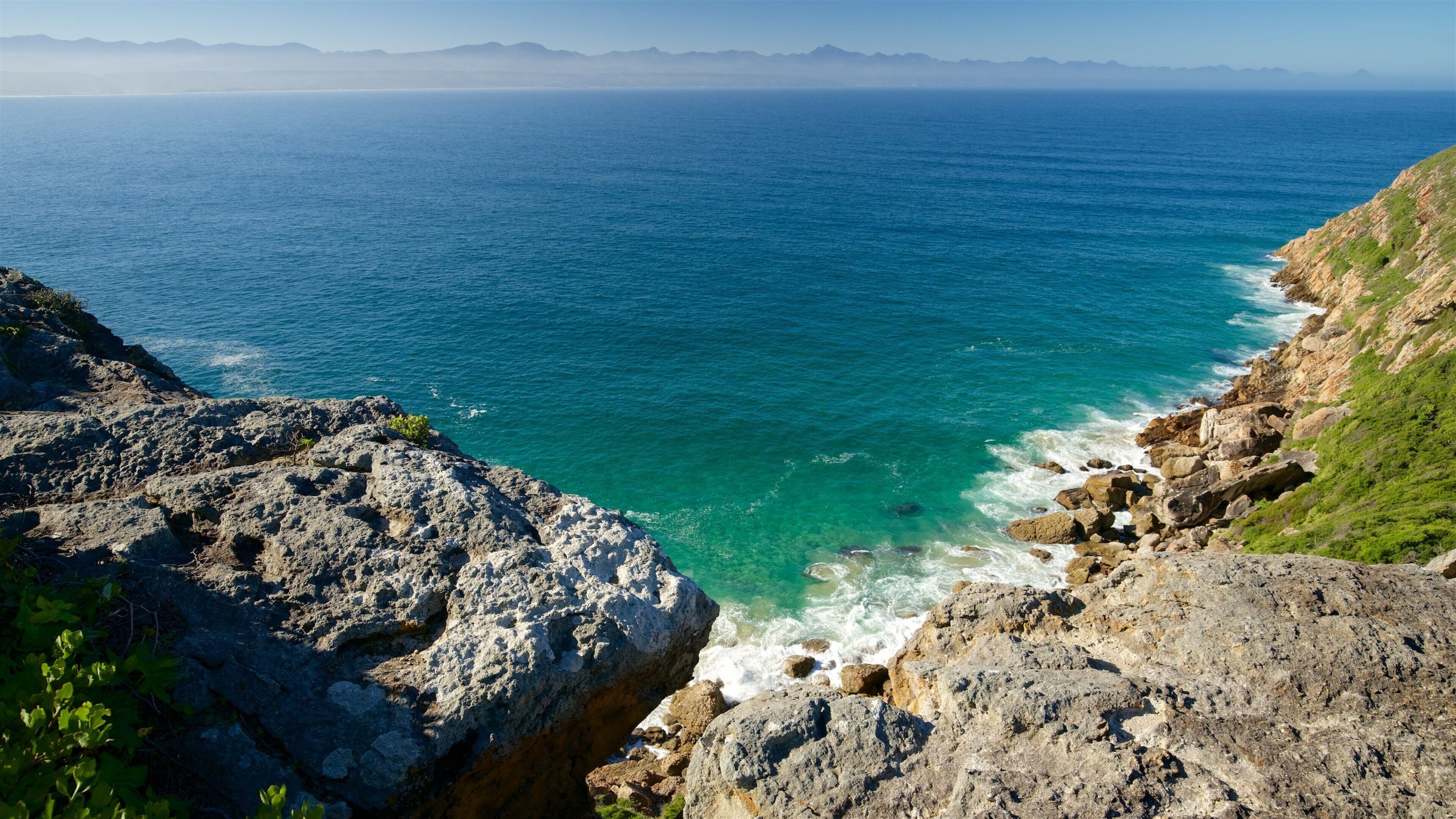 Plettenberg Bay som inkluderer stenete kystlinje og landskap
