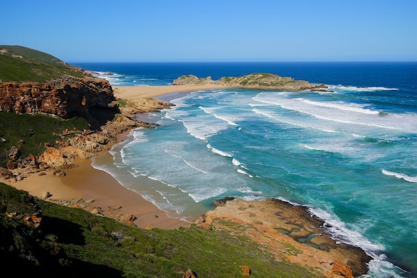 Eine Küstenlandschaft mit Klippen, einem Sandstrand und dem Ozean.
