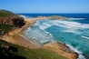 A coastal landscape with cliffs, a sandy beach, and the ocean.