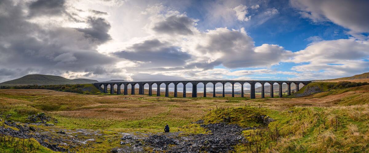 A viaduct over a valley with a person standing in the foreground.