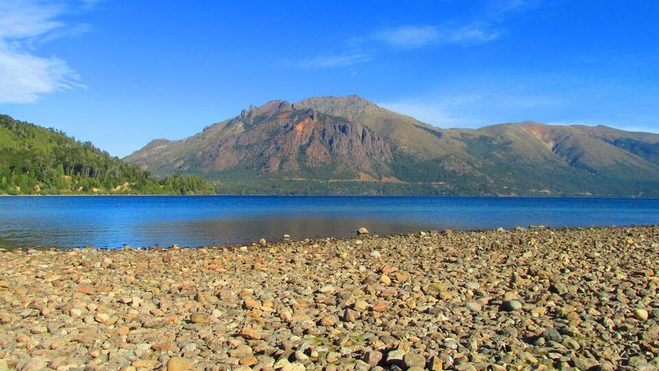 A rocky shoreline with a mountain in the background.