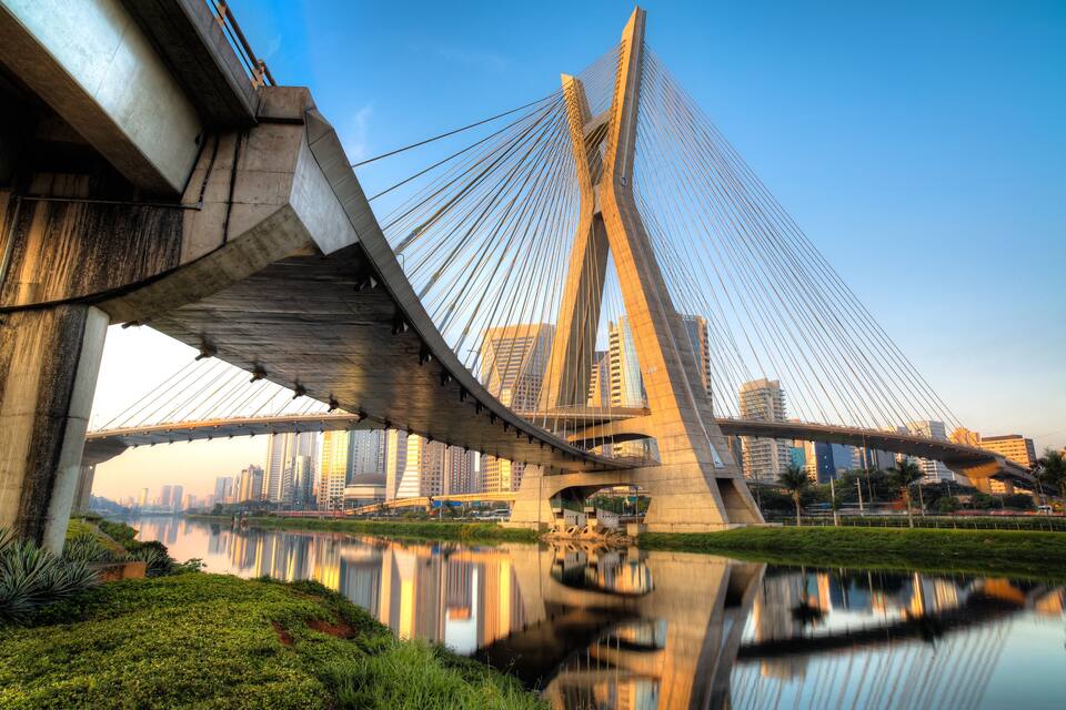 Un puente atirantado con un paisaje urbano de fondo.