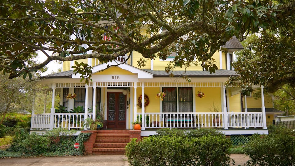 Una casa amarilla con porche, número 916, rodeada de vegetación.