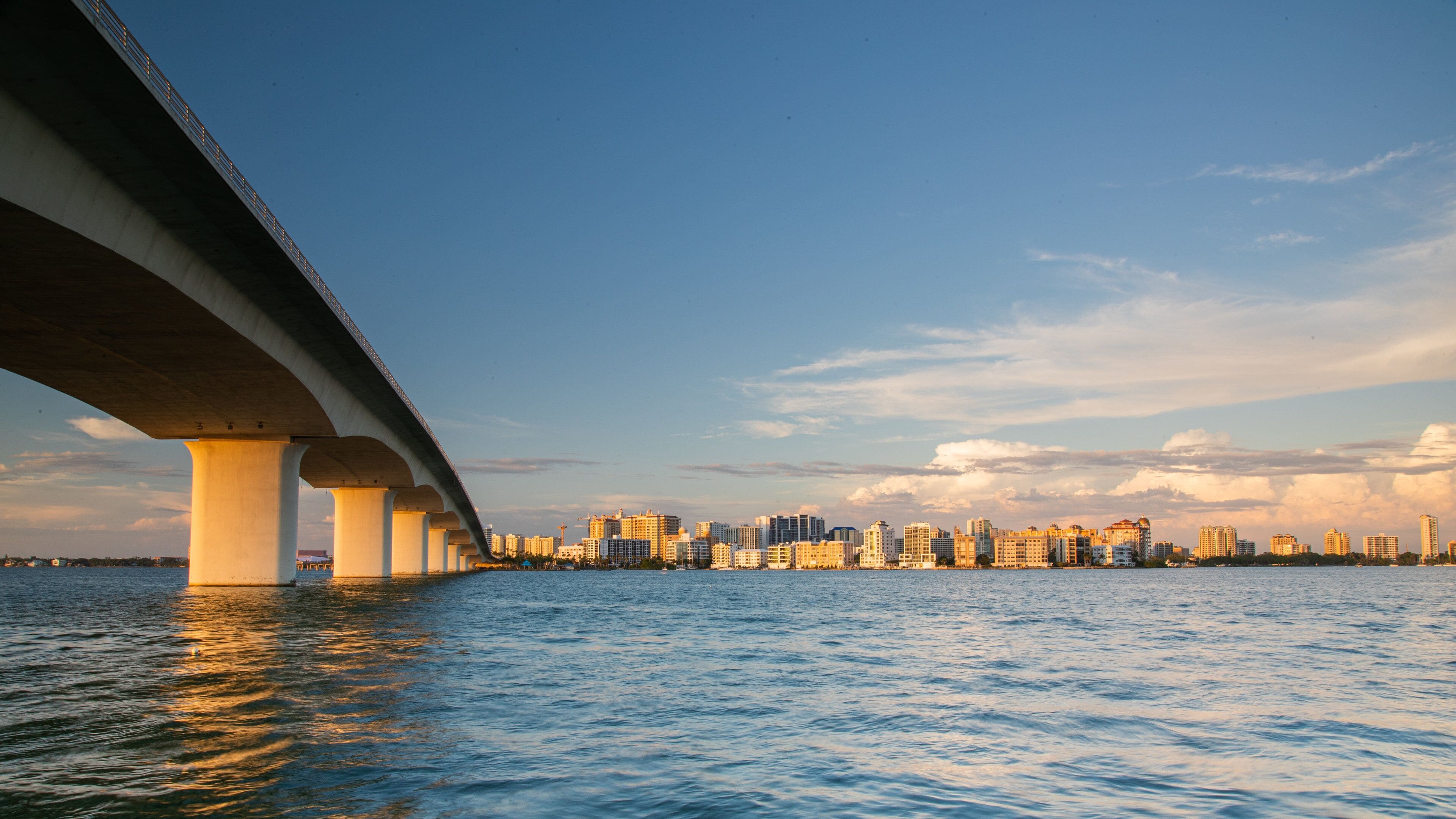 A bridge over water with a city skyline in the background.