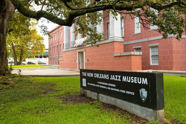 Schild des New Orleans Jazz Museum, umgeben von üppigem Grün und einem großen Baum.