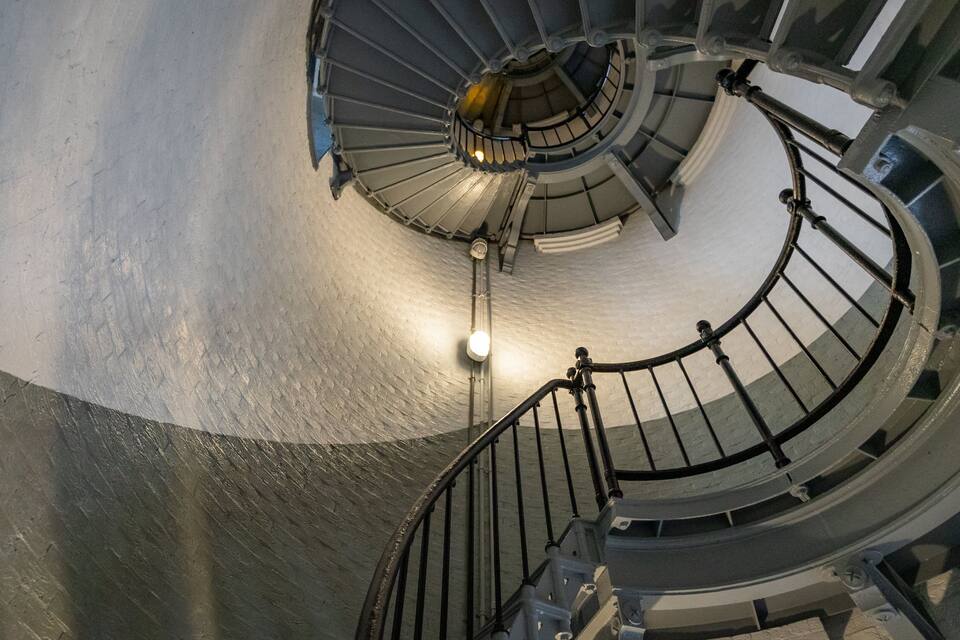 A spiral staircase with metal railings and a light fixture at the center.