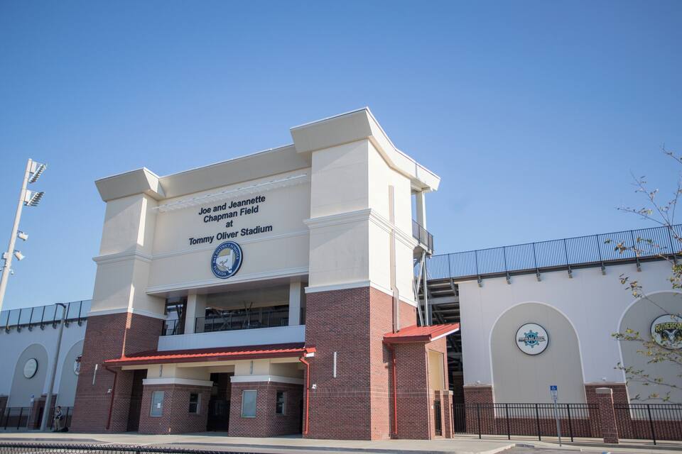 A stadium with a sign reading "Joe and Jeannette Chapman Field at Tommy Oliver Stadium."