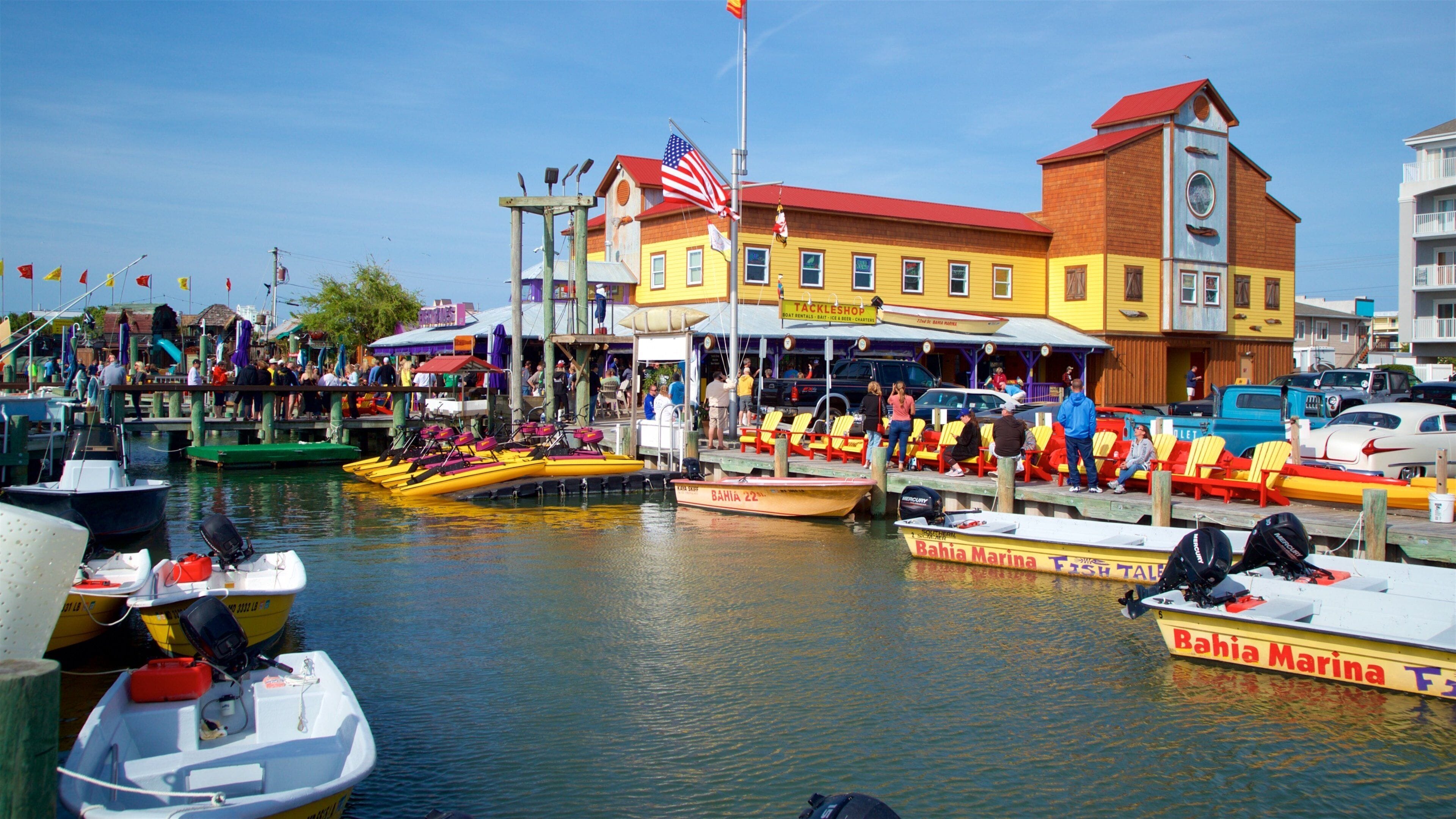 Un port de plaisance avec des bateaux aux couleurs vives, un restaurant appelé Tackleshop et un bateau de la marque Bahia Marina.