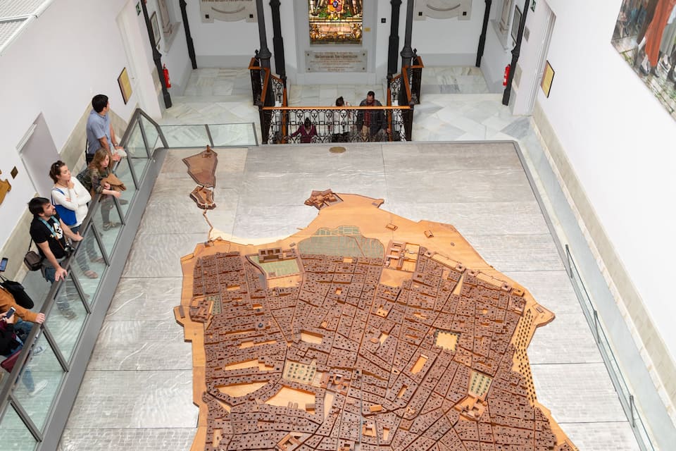A large wooden model of a city layout in a museum.