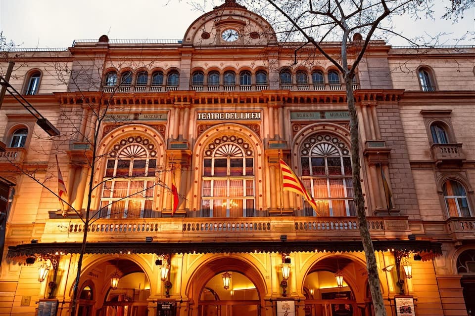A historic theater building with ornate architecture, arched windows, and a prominent flag.