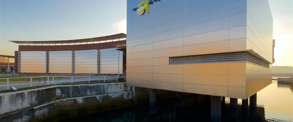 A modern building with a glass roof and a sign that reads "Aquario de Galicia."