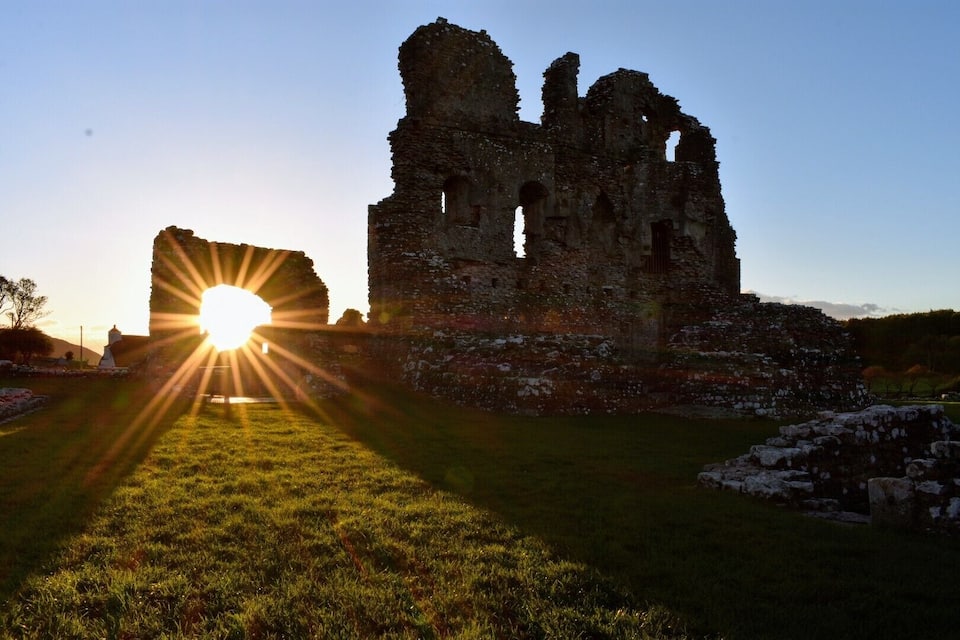 A ruined castle with a sun setting in the background.