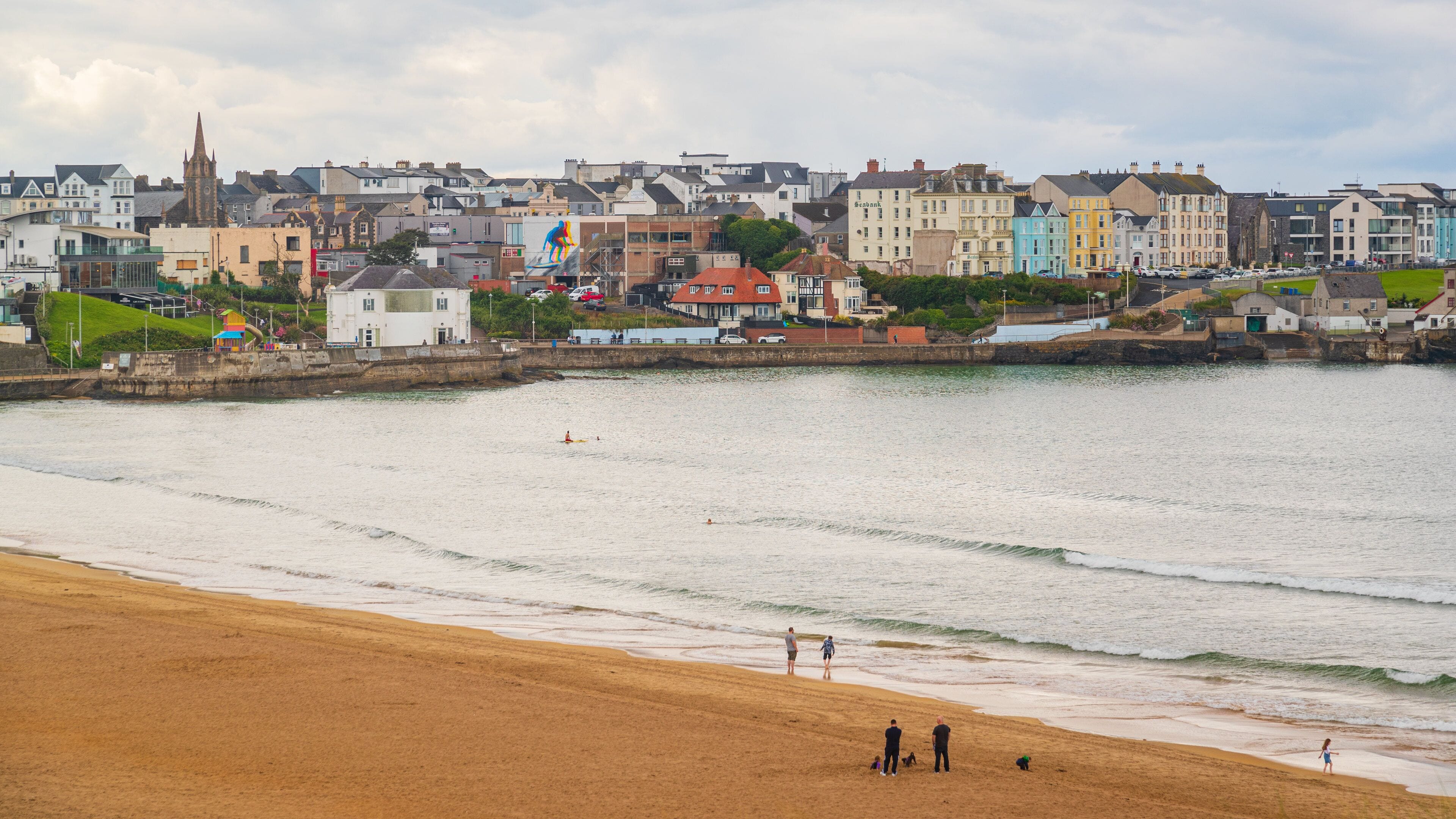 Bushmills which includes a coastal town, a beach and general coastal views