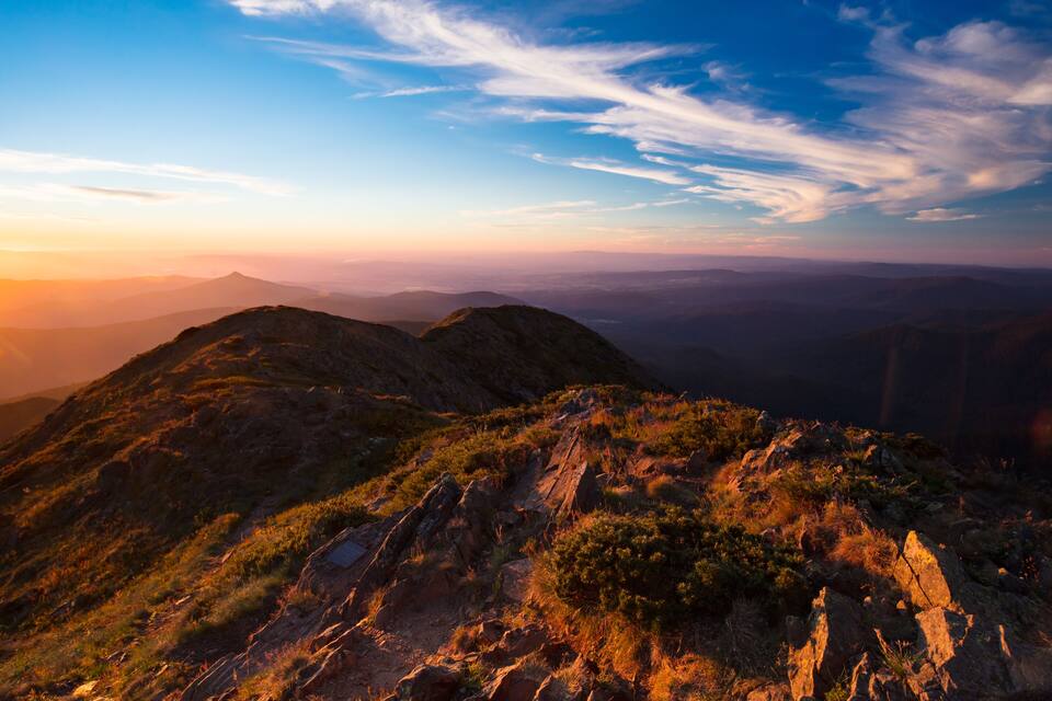 A mountainous landscape with rocky terrain and sparse vegetation under a clear sky.