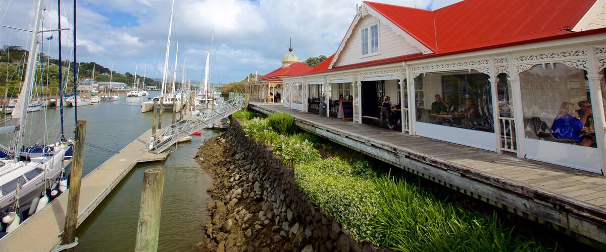 A waterfront with boats docked, a pier with a red-roofed building, and greenery along the shore.