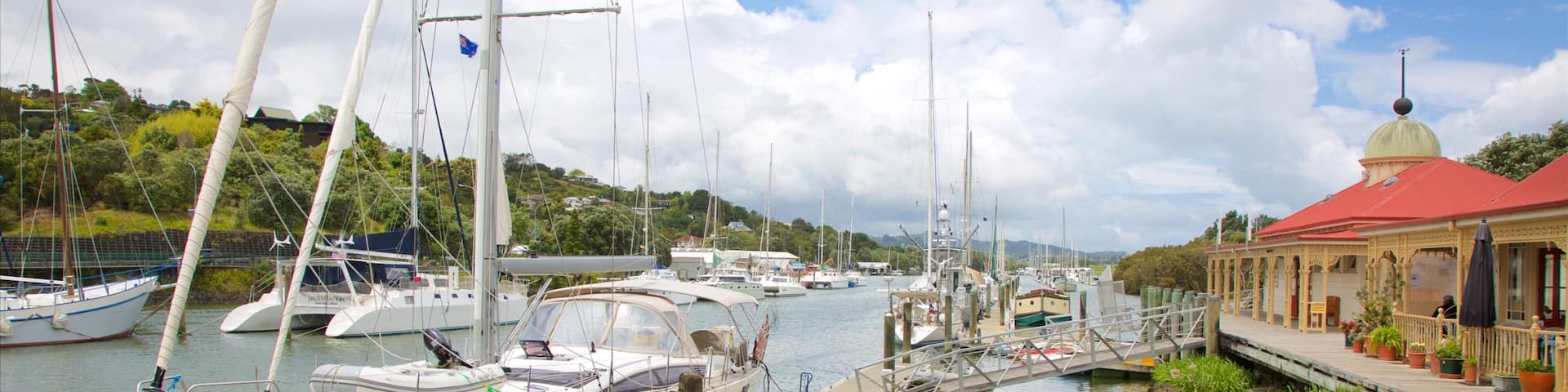 A marina with several sailboats docked, a small bridge, and a restaurant named "Nevo's Restaurant & Bar" with a red roof.