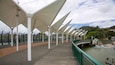 A waterfront promenade with white canopies and a bridge over the water.