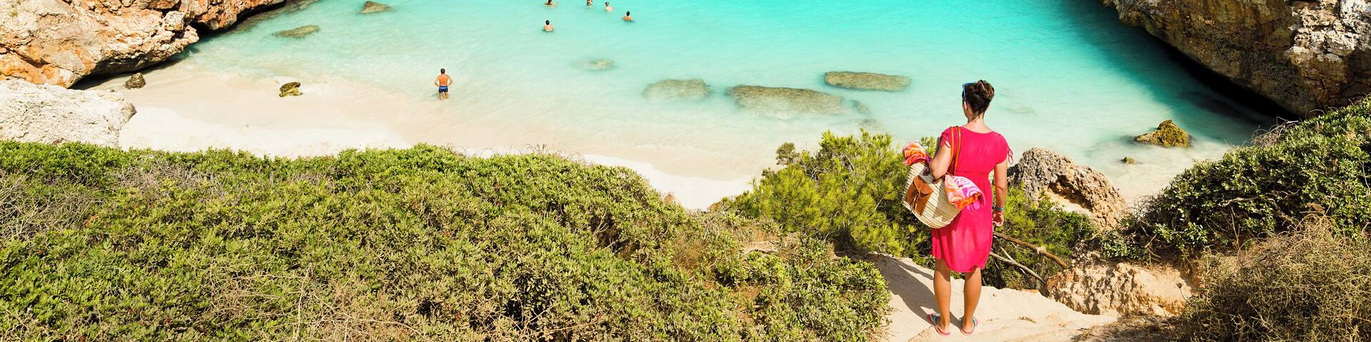 Un paisaje costero con una bahía turquesa, acantilados rocosos y una playa.