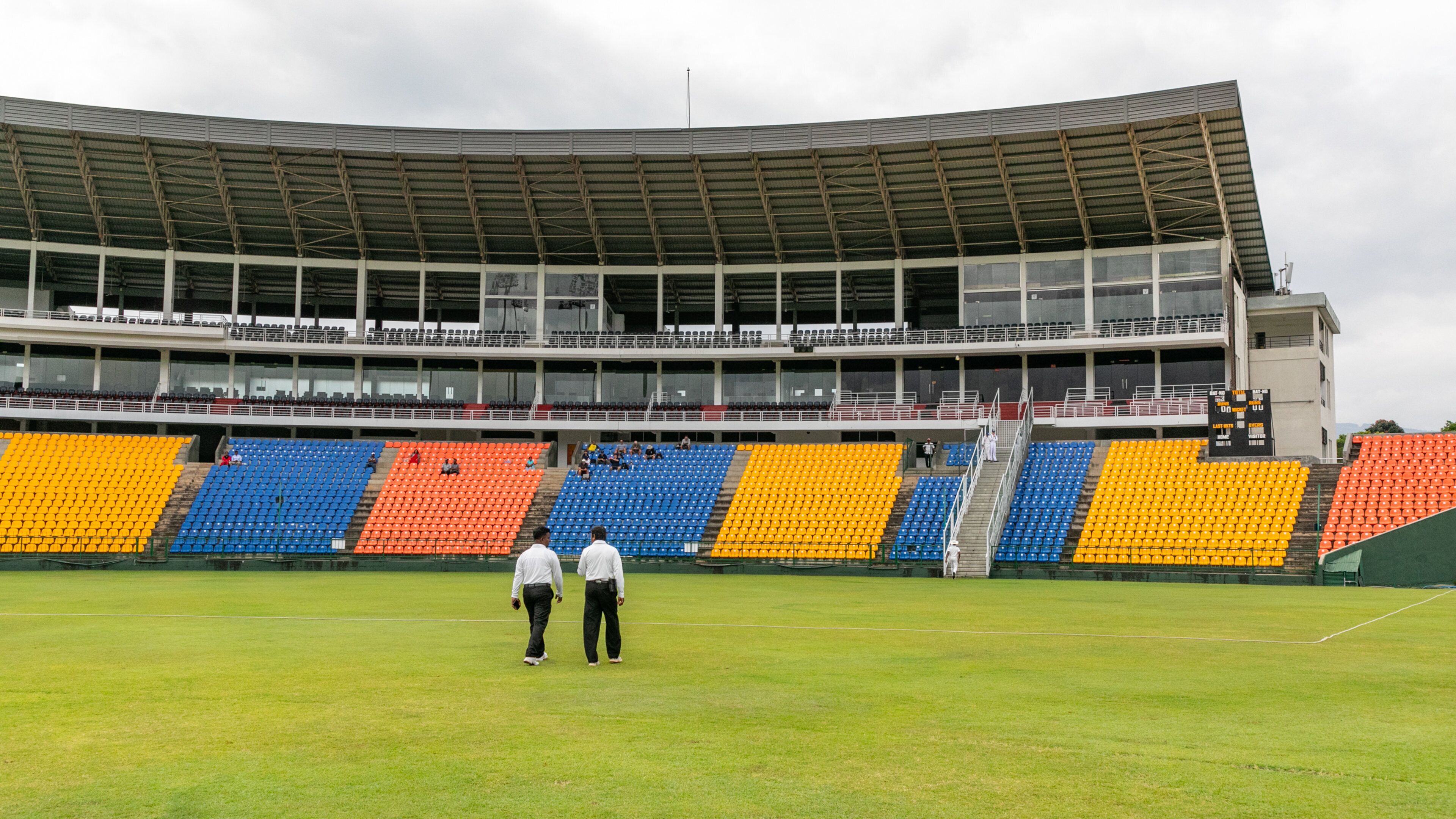 A stadium with tiered seating and a green field.