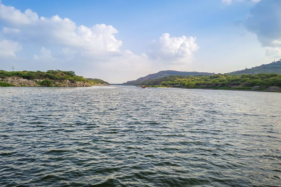 A river with calm waters, surrounded by green hills and a clear sky.
