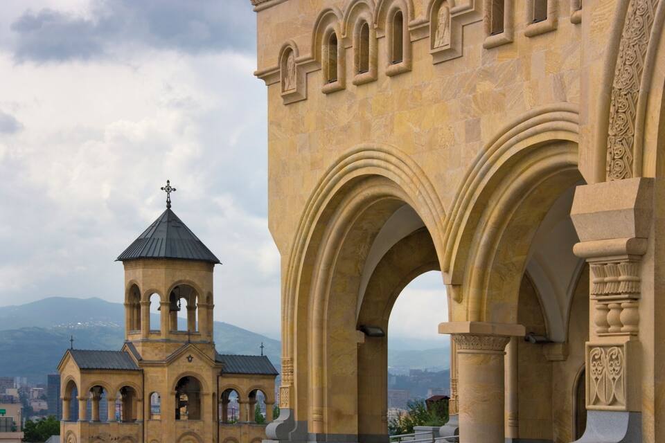 Un edificio histórico de piedra con arcos y un campanario.