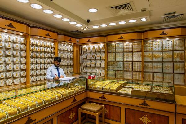 A jewelry store with gold and white jewelry displayed on shelves and in glass cases.