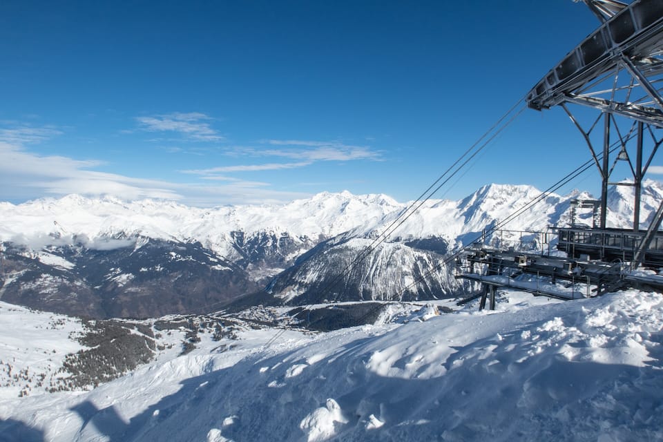 A snow-covered mountain range with a ski lift in the foreground.