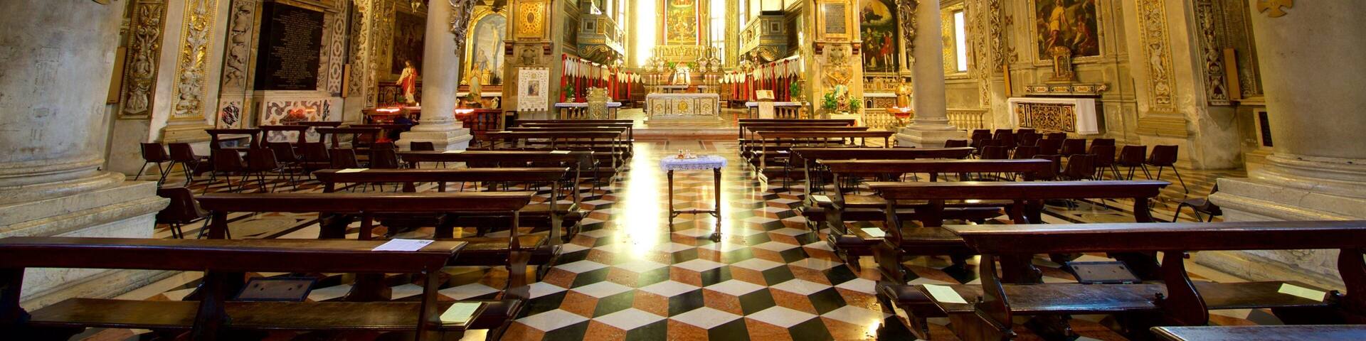 An ornate church interior with high ceilings, detailed frescoes, and a checkered floor.
