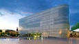 A modern building with a reflective glass facade, a plaza with fountains, and a historic church in the background.