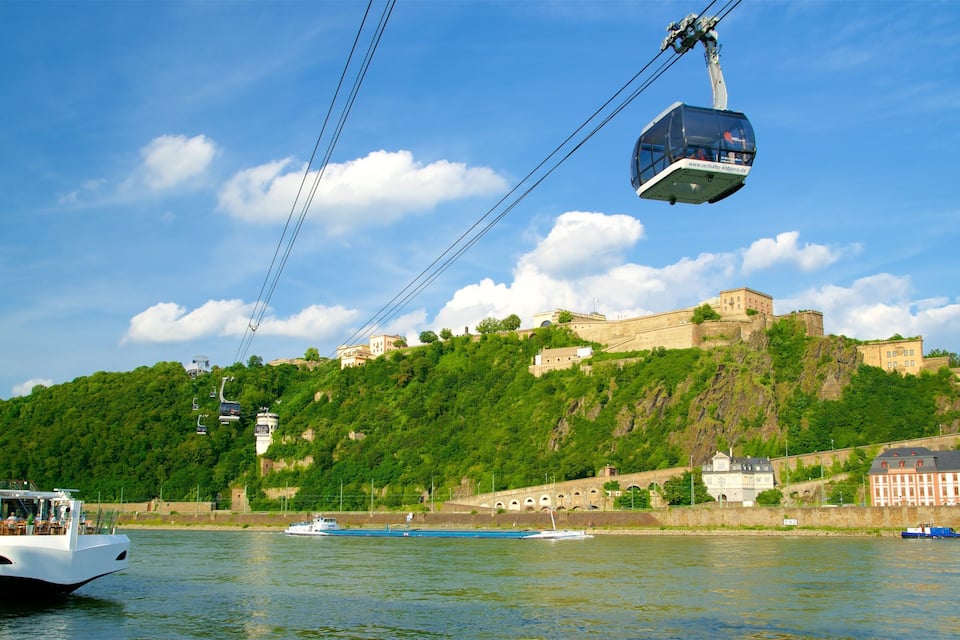 A cable car over a river, a castle on a hill, and boats on the water.
