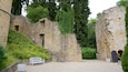 A historical stone structure with ivy-covered walls, a white bench, and a staircase leading up to an arched doorway.