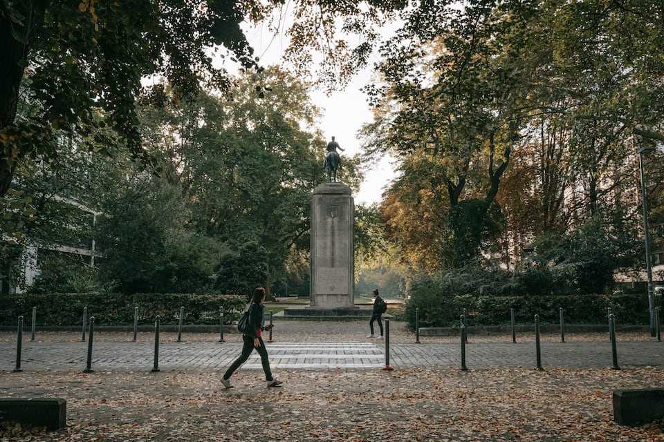 A park with a central monument surrounded by trees and a paved walkway.