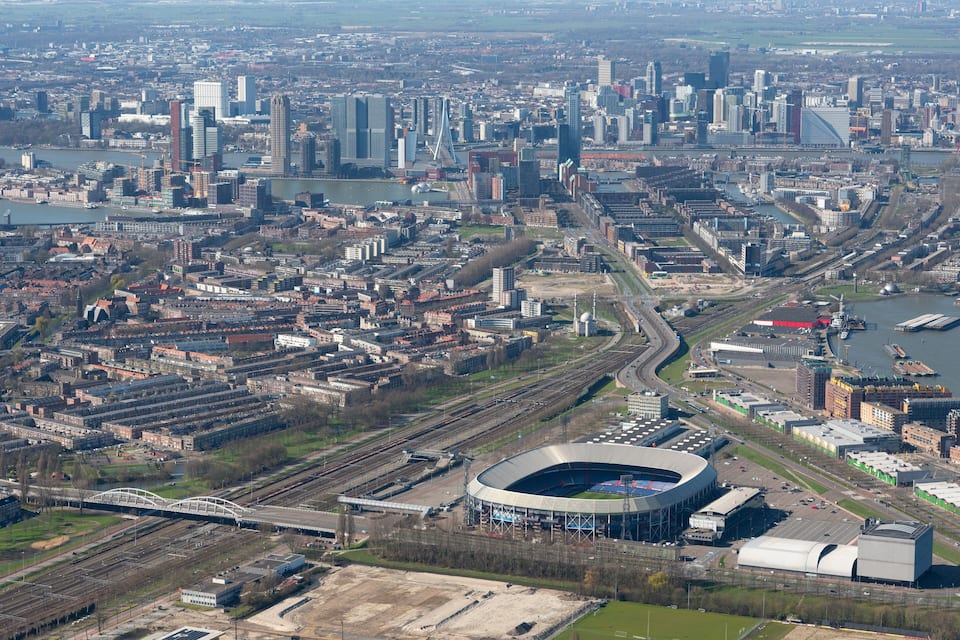 Un paisaje urbano con un estadio destacado, edificios densos y un río.
