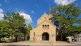 Una iglesia de piedra histórica con techo puntiagudo y una aguja alta.