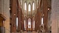L’intérieur d’une cathédrale, avec de hautes fenêtres en arc de cercle et un autel central.