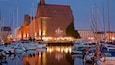 A marina with boats docked in front of a large brick building with a statue on the roof.