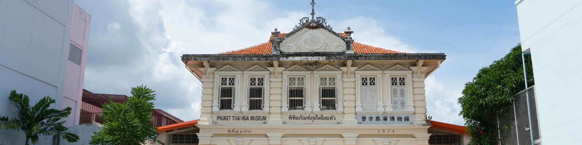 A historic building with a tiled roof and arched entrances, labeled as the Phuket Thai Hua Museum.