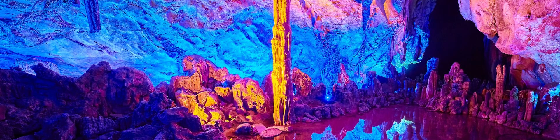 A cave with colorful rock formations and a reflective water surface.