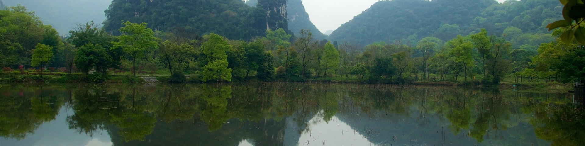Yangshuo Park featuring mountains, mist or fog and a lake or waterhole