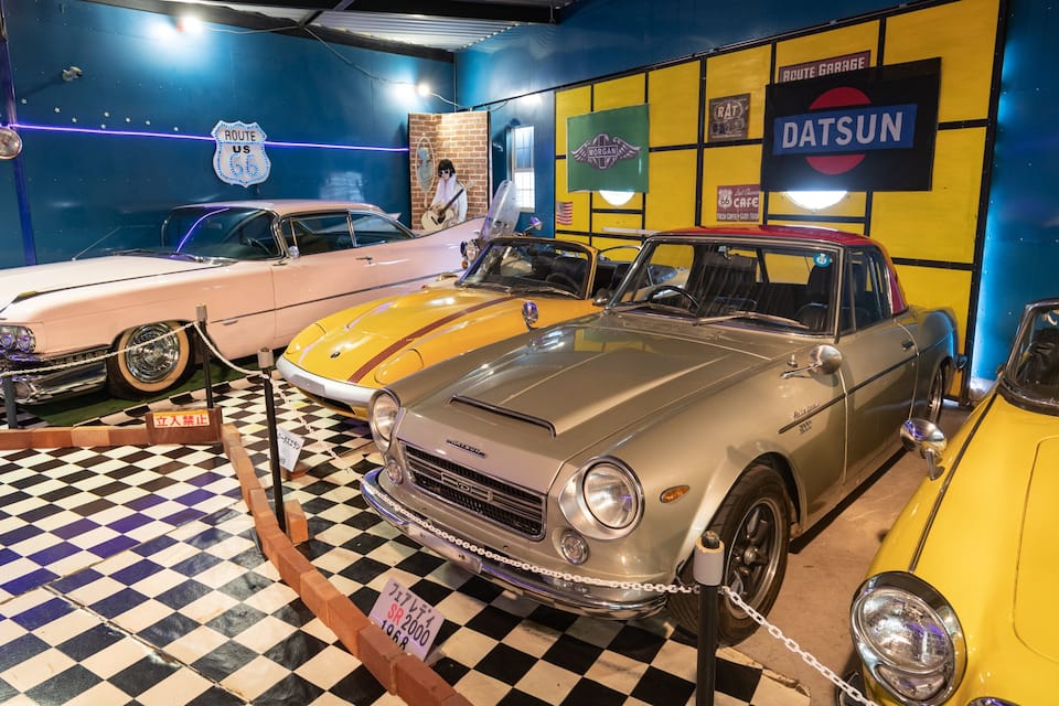 En utställning med veteranbilar, ett golv i svart- och vitrutigt mönster, en skylt med texten ”Route 66” och en Datsun-skylt.