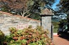 A stone wall with a sign, a stone pillar, and a pathway.