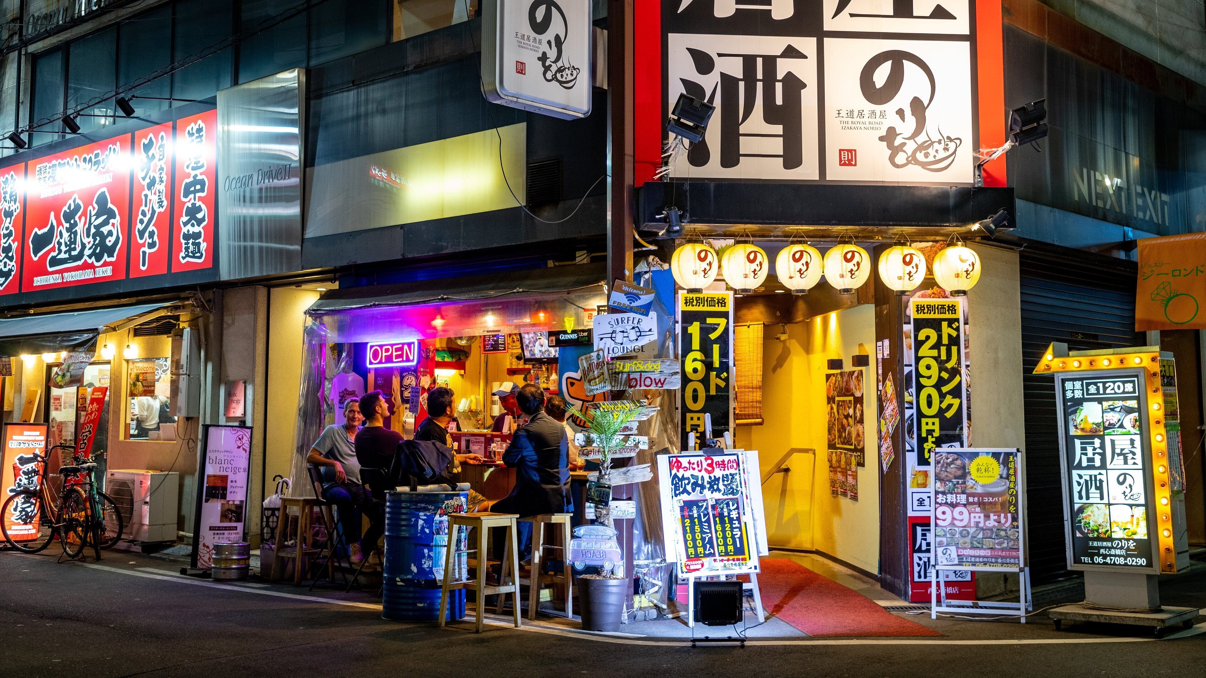 A street with various shops, including a sushi restaurant and a bar.