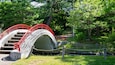 Un pont de pierre avec des garde-corps rouges, situé dans un parc.
