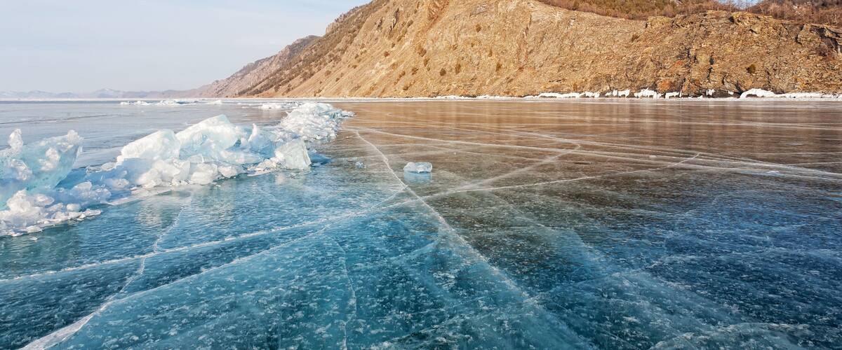 A frozen lake with ice floes and a mountain in the background.