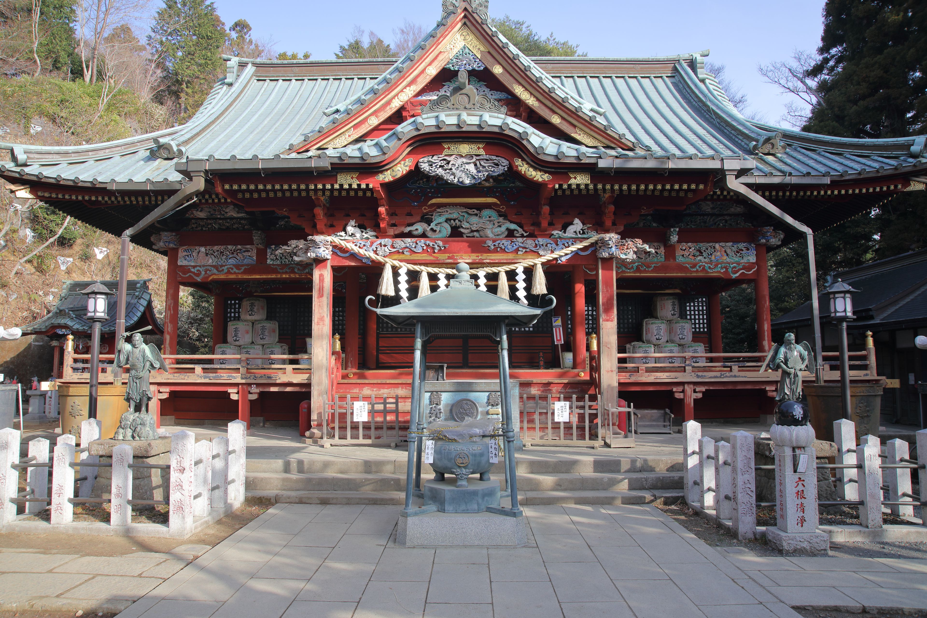 Un templo japonés tradicional con arquitectura ornamentada, una estatua central y piedras conmemorativas.